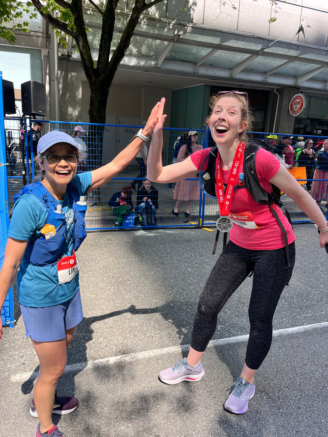 Two  Striderz run club runners crossing BMO finish line with spectators in the background