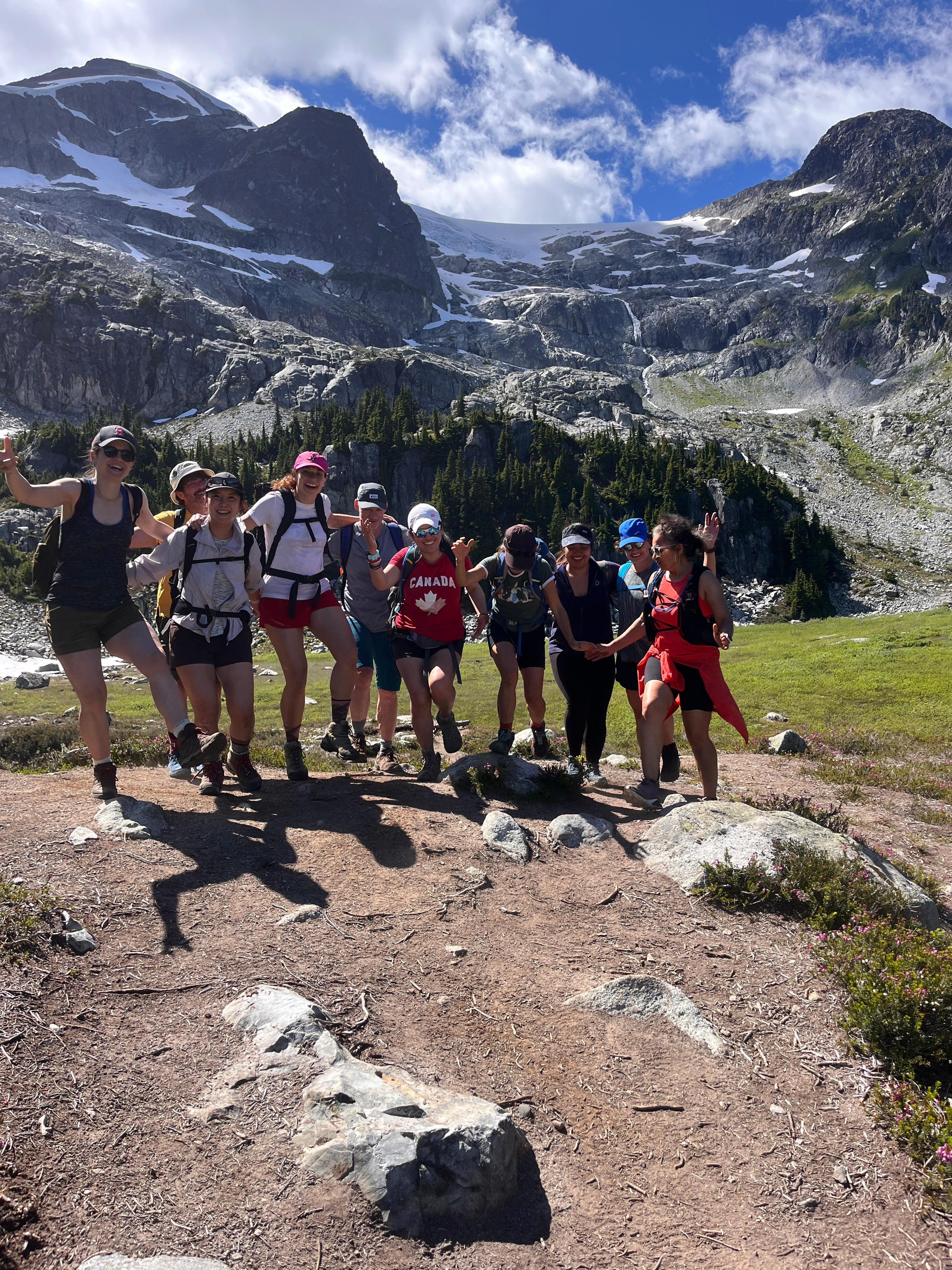 Group of Striderz run club runners on a mountain trail with snow-capped peaks in the background