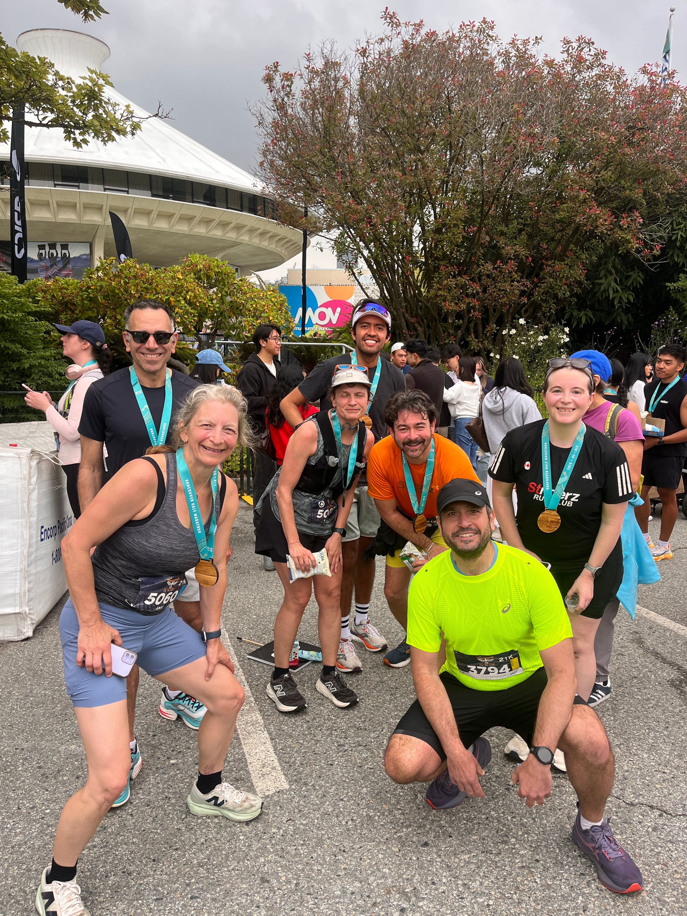 Group of runners posing together after a race, with trees and a building in the background.