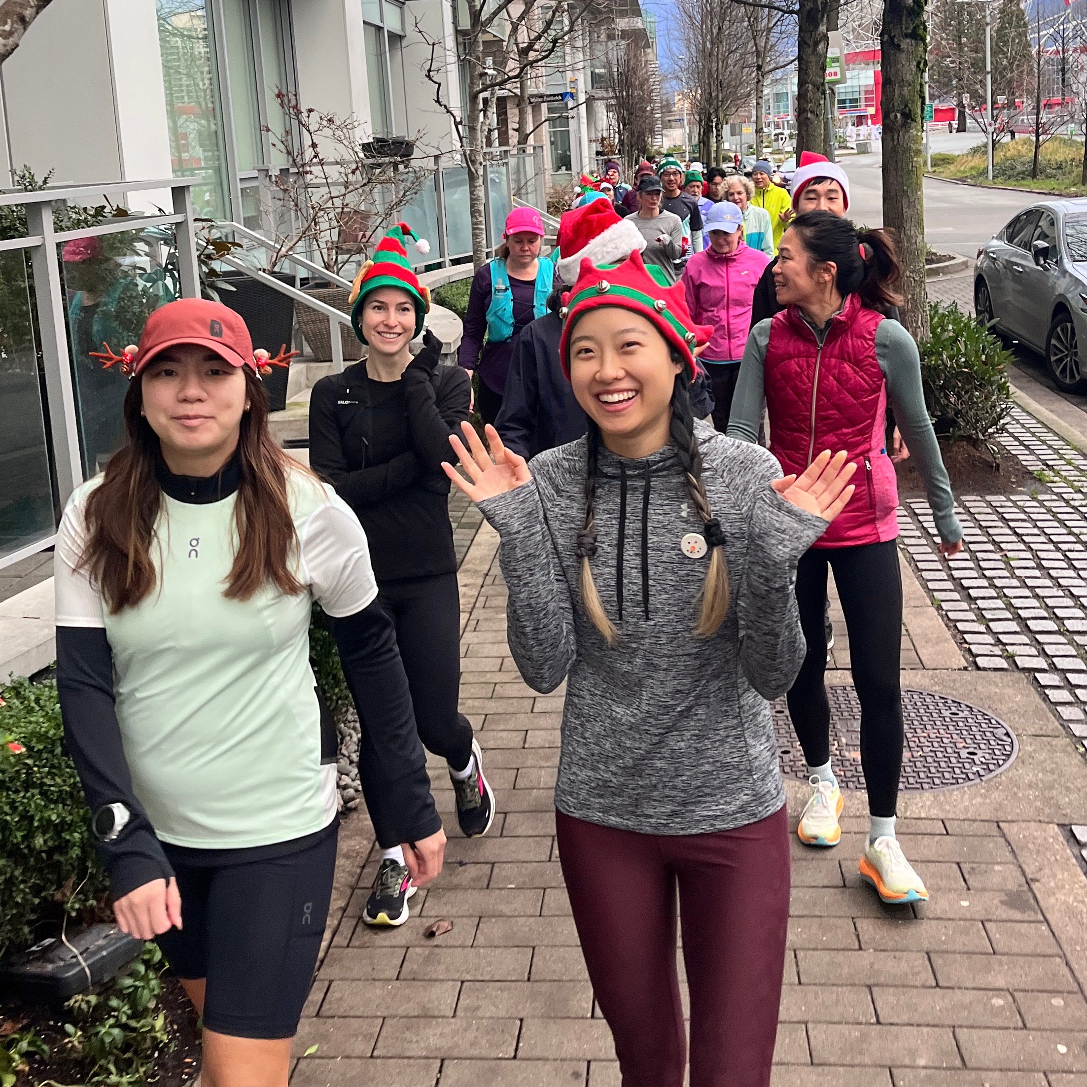 Group of Striderz run club in festive hats, walking outdoors on a sidewalk.